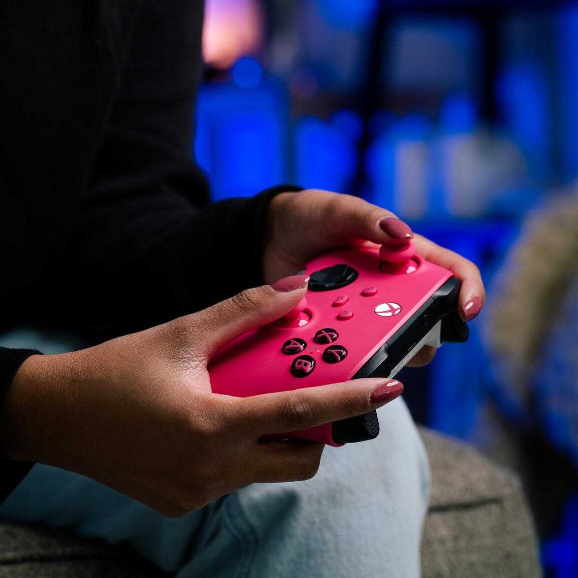 Person holding a pink Xbox Series X wireless controller in a gaming setup.