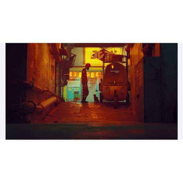 Urban alley with neon signs and a person standing under colorful lights.