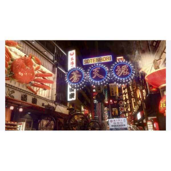 Vibrant night cityscape from Yakuza Kiwami 2 featuring neon signs and bustling streets.