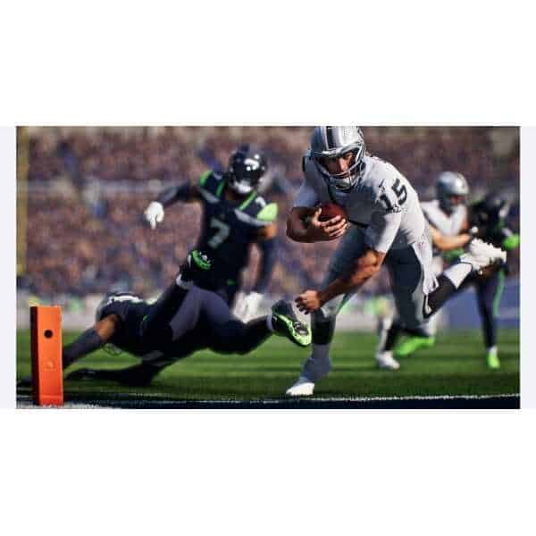 Football player running with ball near end zone, evading defenders.