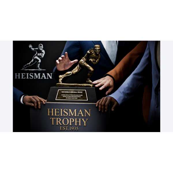 Heisman Trophy award presented at a formal event with people in suits.