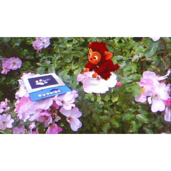 EyePet toy among pink flowers, promoting interactive gaming experience.