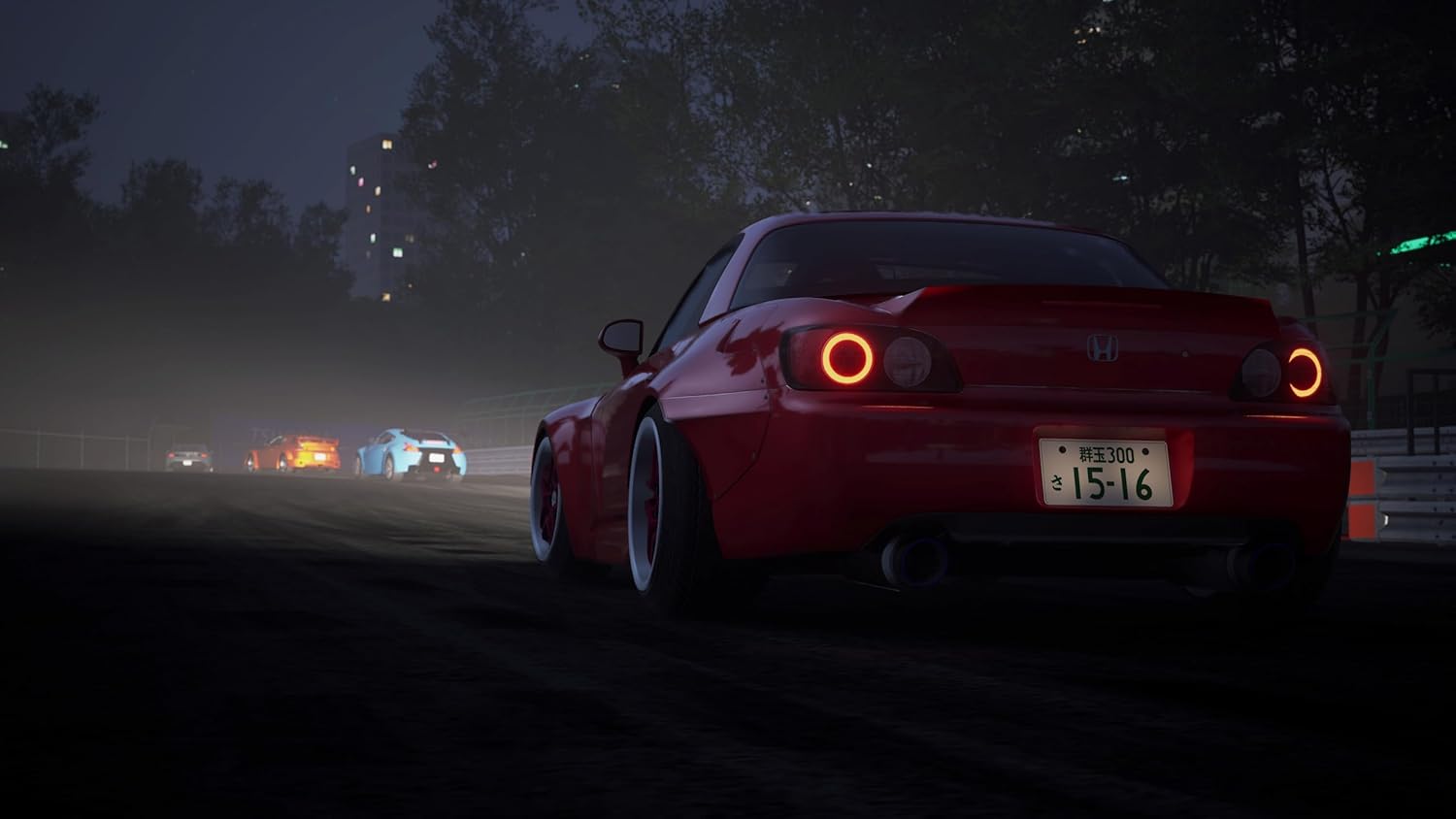 Racing car with red paint and custom wheels on a dark city street at night.
