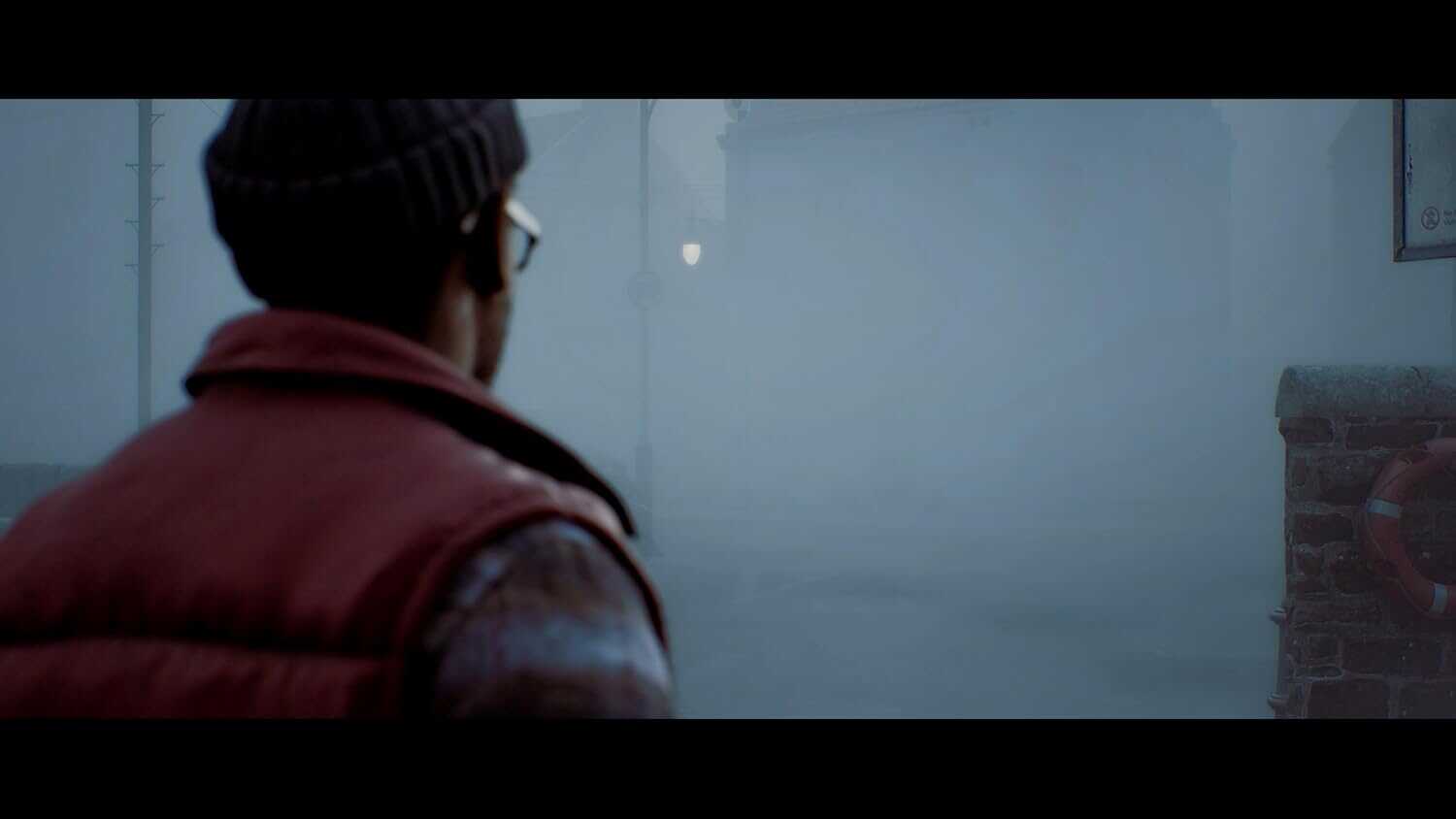 Person in a dark, foggy environment with a beanie and glasses.