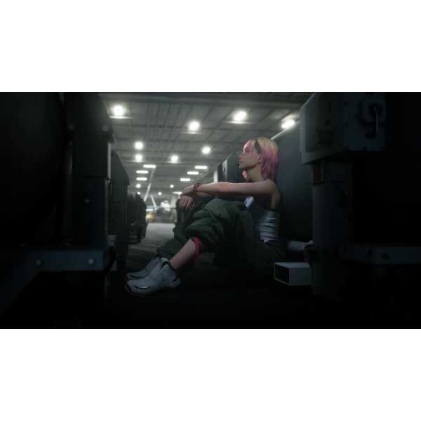 Young woman with pink hair sitting on the floor in a parking garage at night.