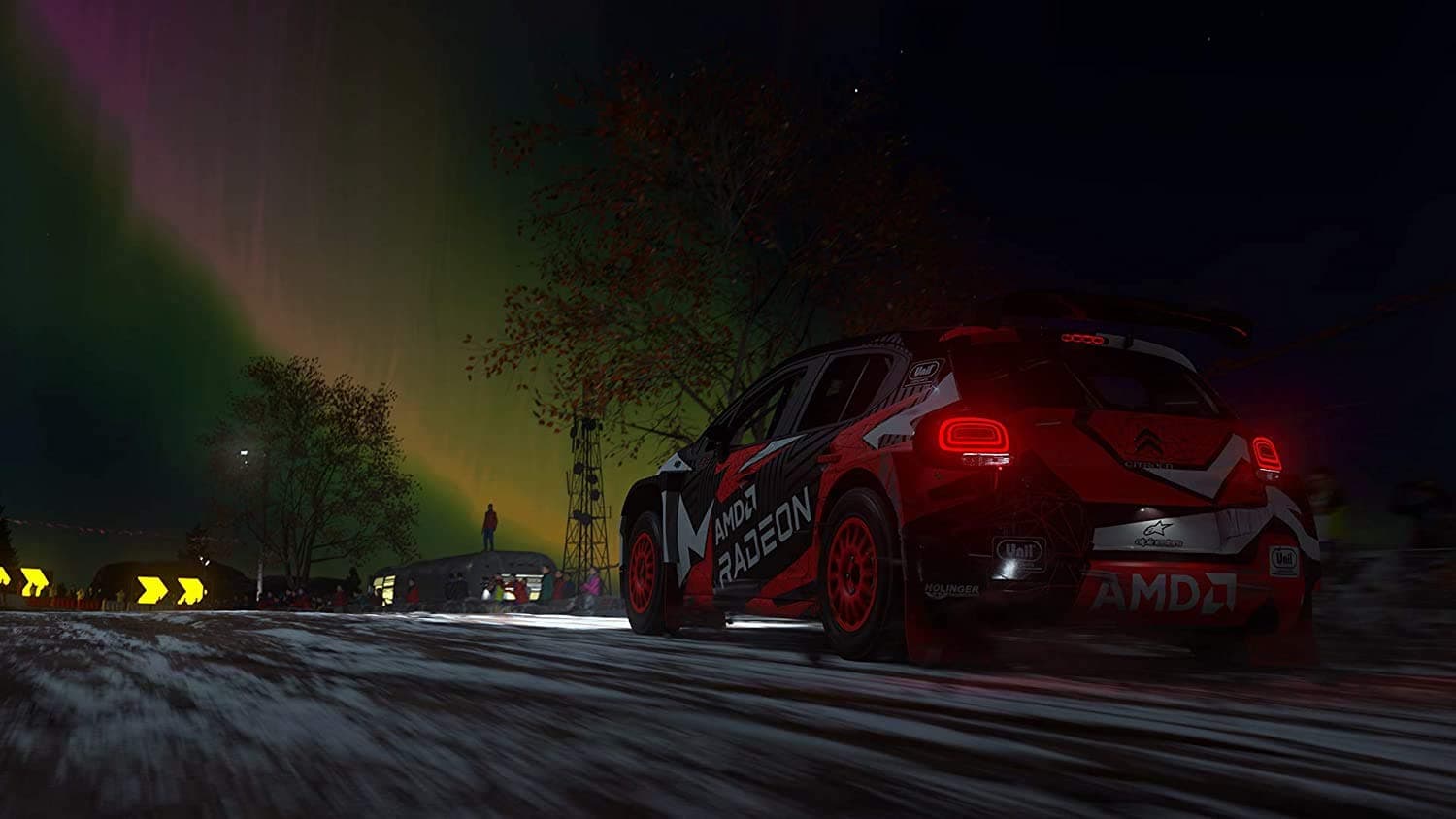 High-performance rally car racing at night with vibrant northern lights in the background.