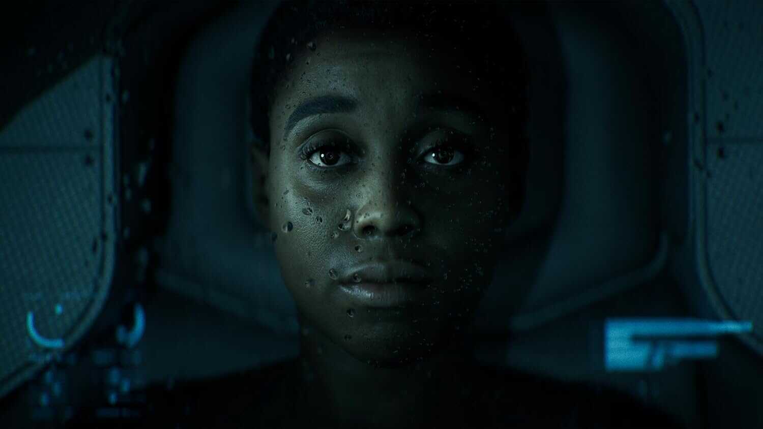 Close-up of a woman with water droplets on her face in a sci-fi setting.