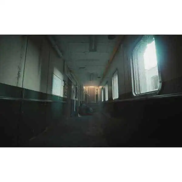 Abandoned industrial corridor with dim lighting and foggy atmosphere.