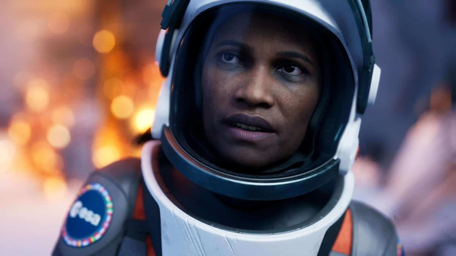 Astronaut wearing a helmet, ready for space exploration, with a blurred fiery background.