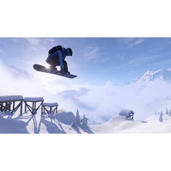An adventurous snowboarder jumps over snow obstacles in a snowy mountain landscape.