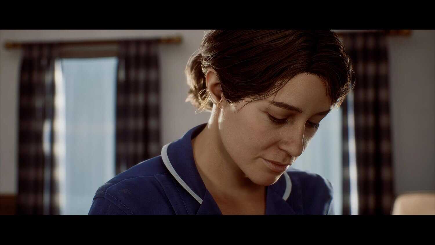 Close-up of a woman with short brown hair looking down, in a dimly lit room.