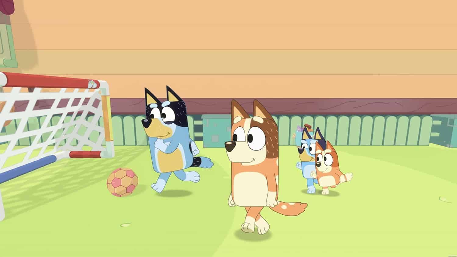 Cartoon dogs playing soccer on a grassy field with a goal and ball.