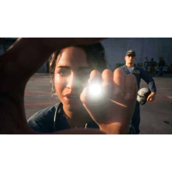 Female pilot holding a flashlight with a male pilot in the background.