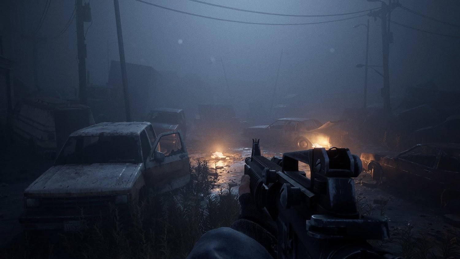 Post-apocalyptic urban scene with destroyed vehicles and dark, foggy atmosphere.