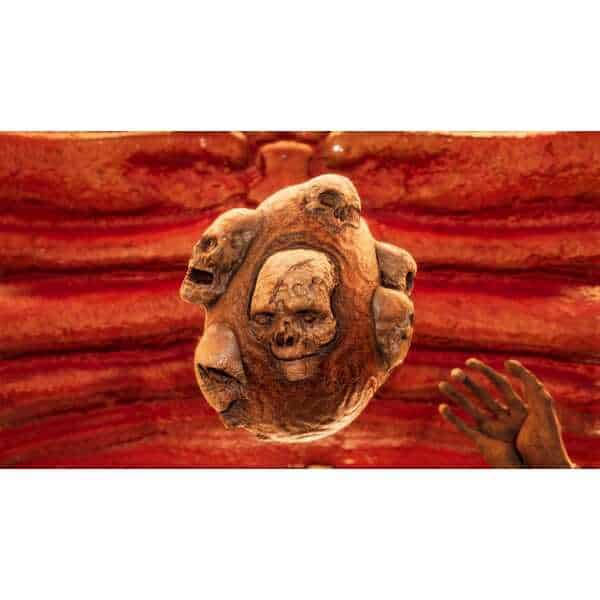 Ancient skull carving with multiple faces, symbolizing consciousness and death.