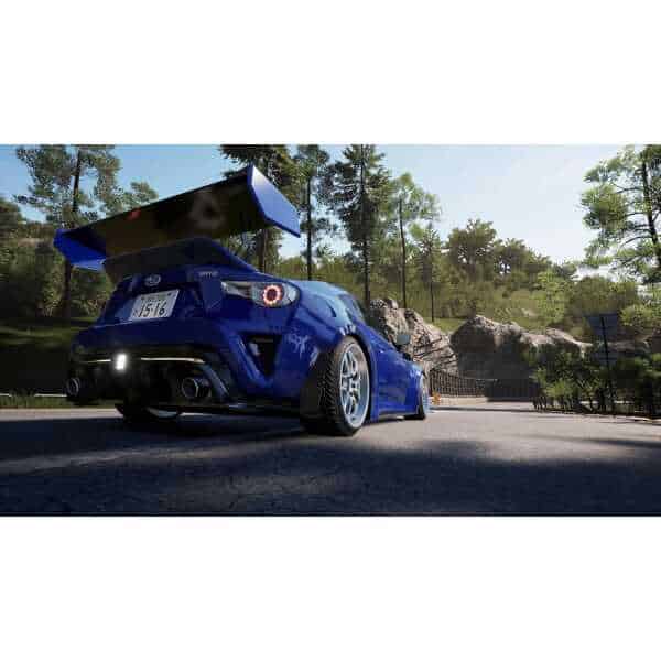 Blue racing car with large rear wing on scenic road, showcasing high-performance vehicle.
