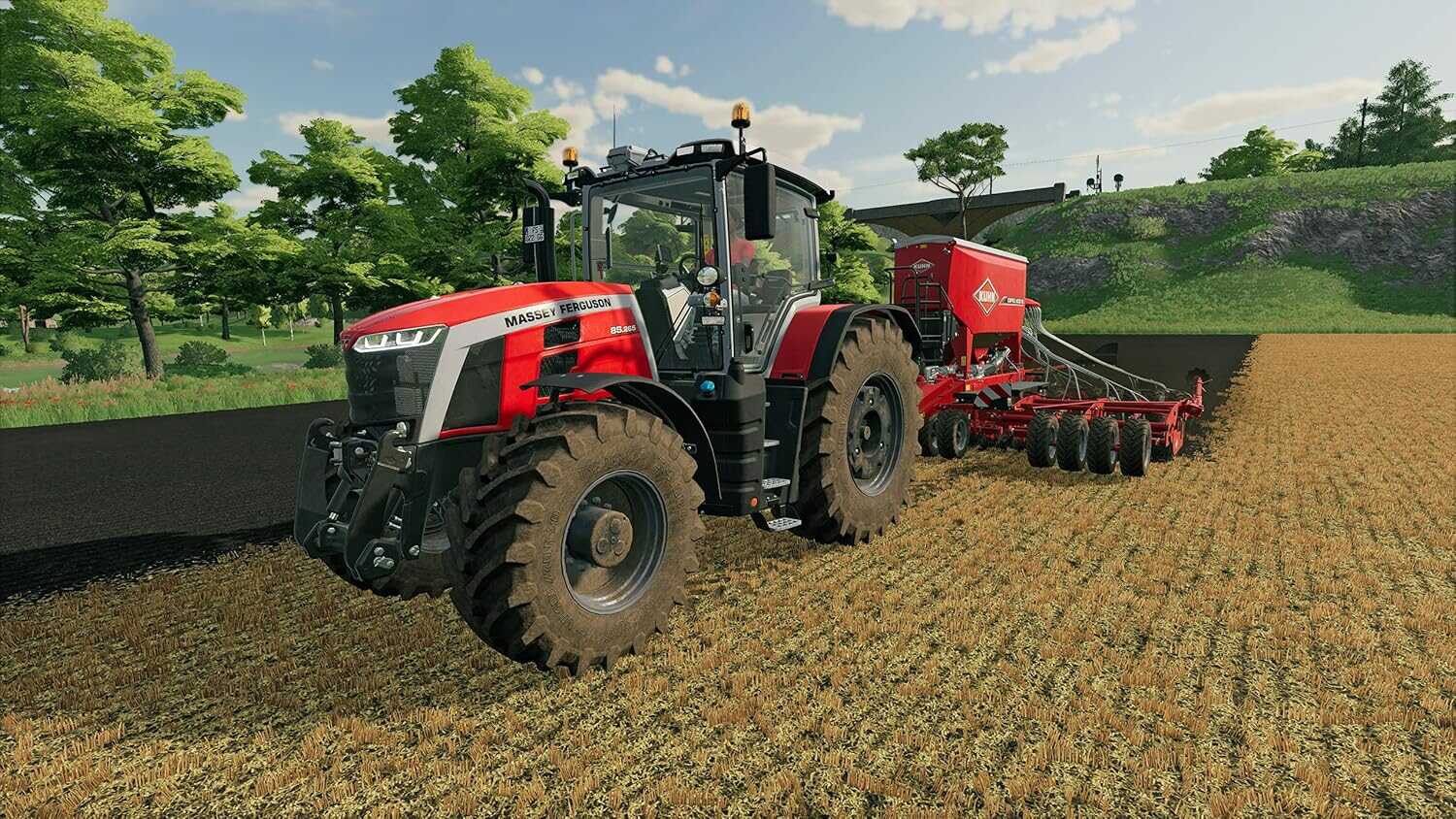 Red tractor with seeder attachment working on farmland in Farming Simulator 22.
