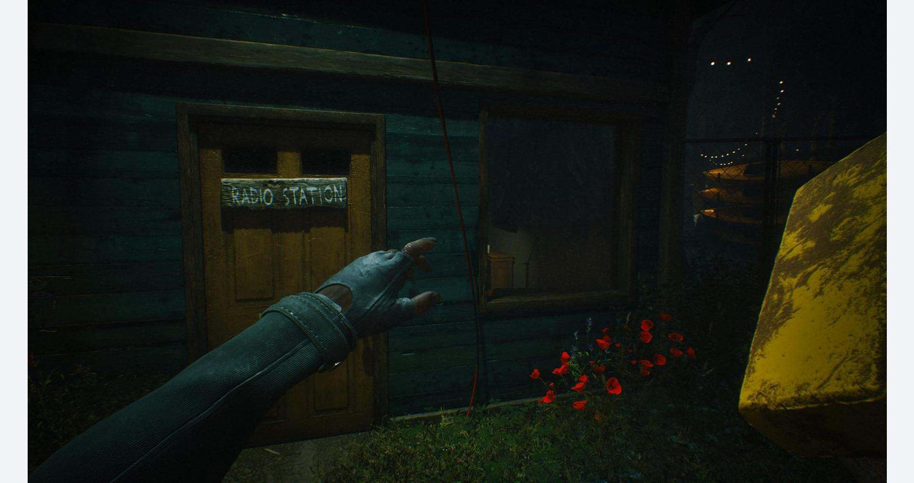 First-person view of a hand reaching towards a radio station sign outside a wooden building at night.