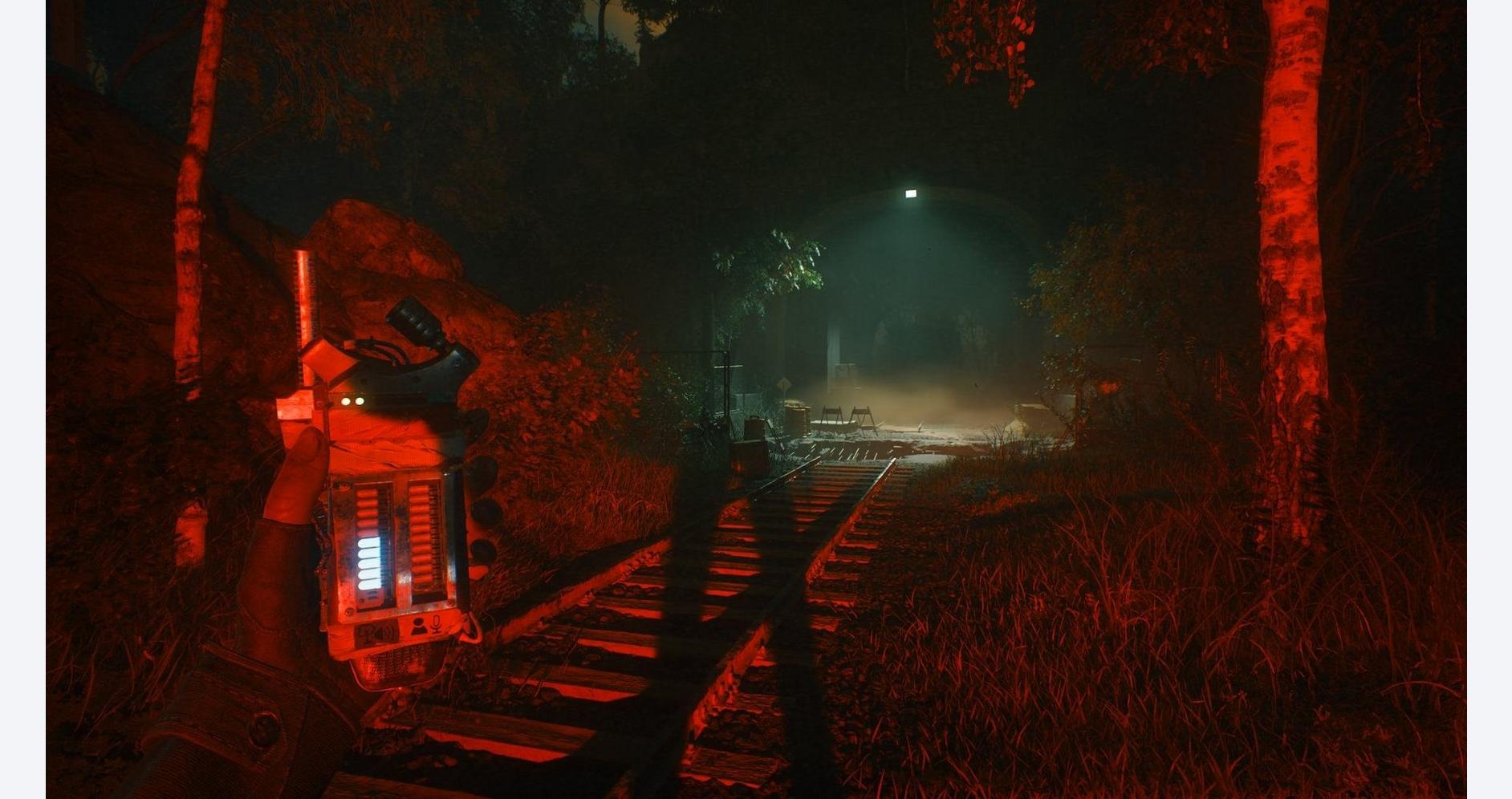 Nighttime forest scene with railway tracks and mysterious red-lit device.