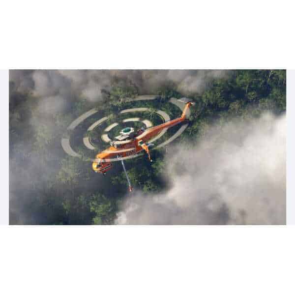 Helicopter spraying water over forest fire for firefighting efforts.
