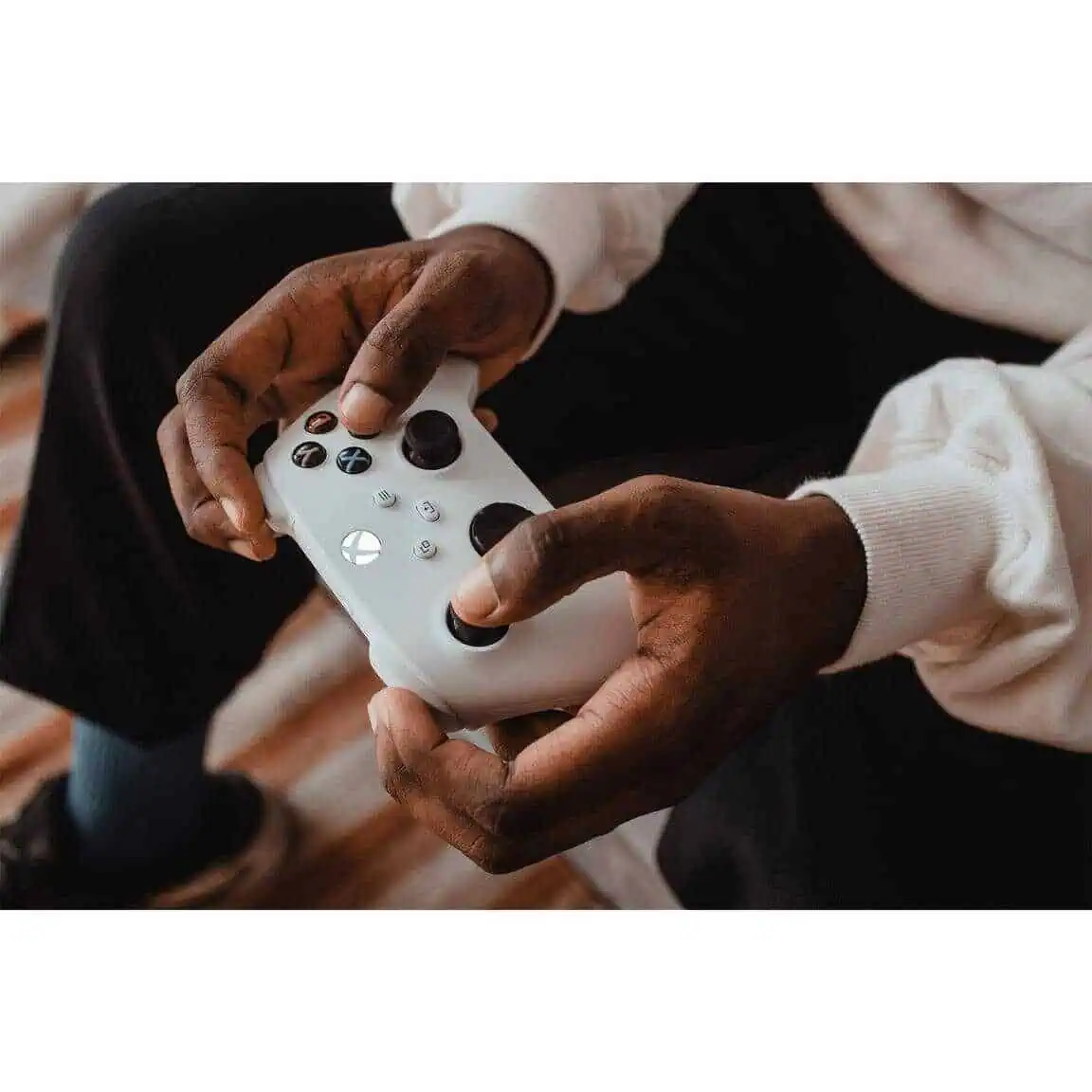 Person holding a white Xbox Series X wireless controller with black buttons.