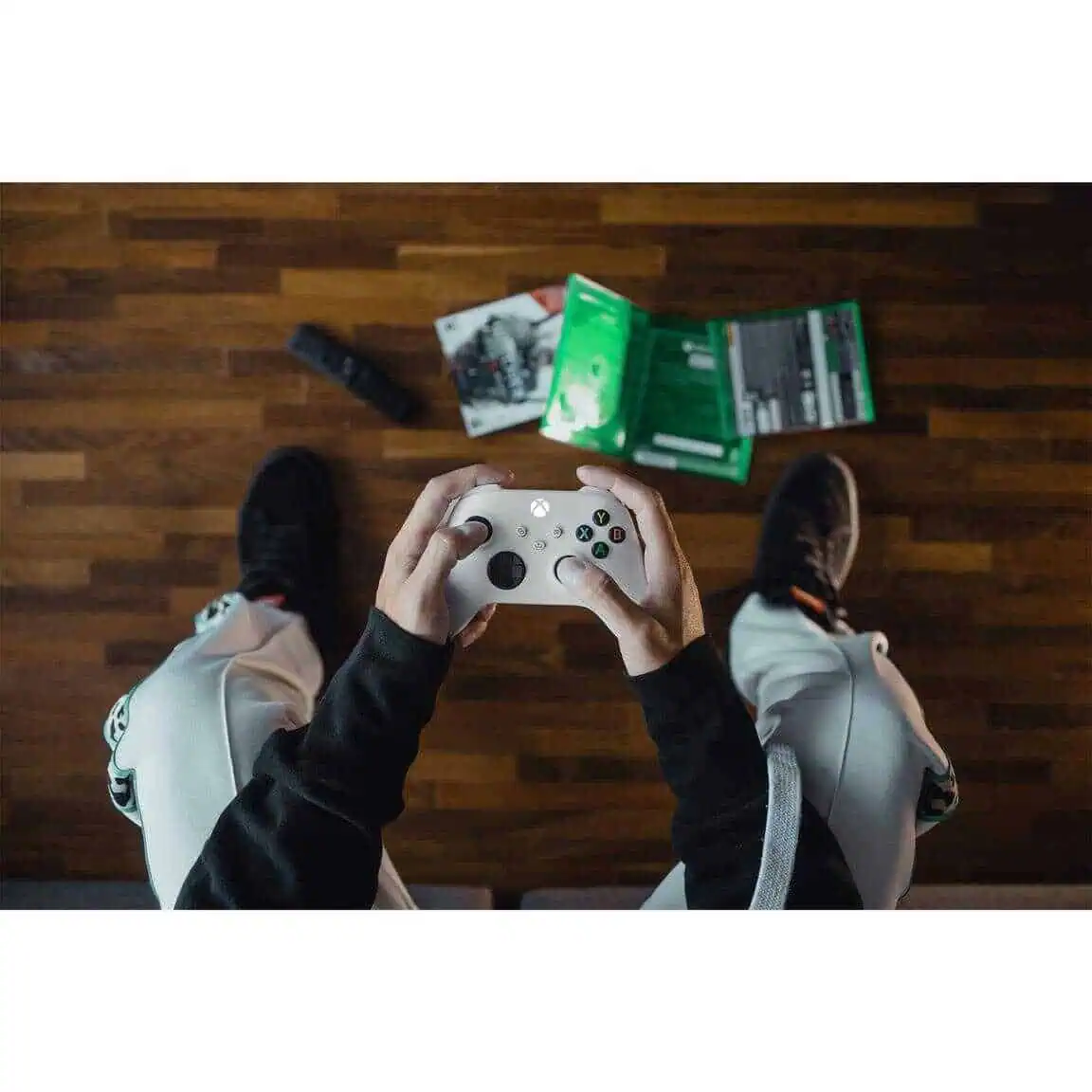 Person holding Xbox Series X Wireless Controller - Robot White over wooden floor.
