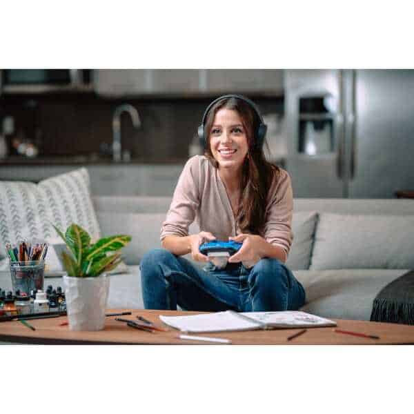 Young woman gaming with Xbox Series X controller and headphones at home.